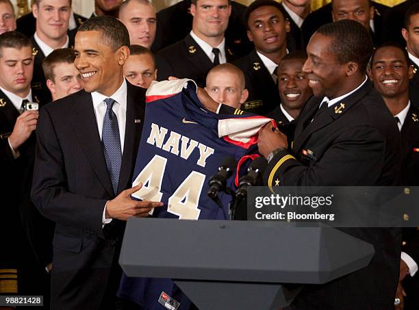 President Barack Obama is presented with the U.S. Naval Academy football jersey by Osei Asante during the Commander in Chief trophy presentation in...