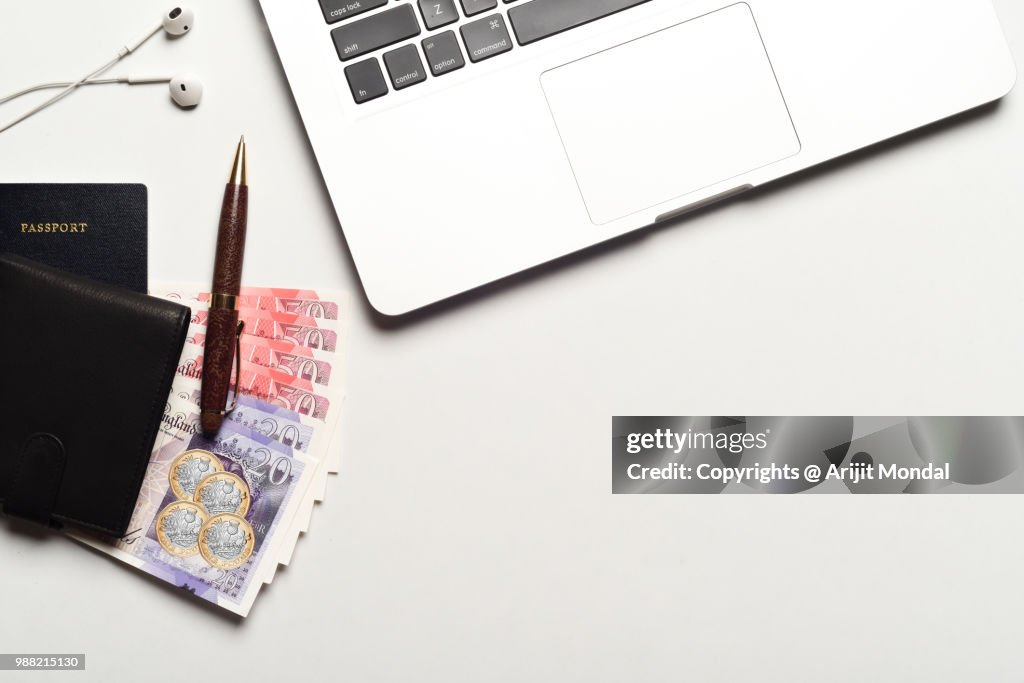 Passport with Great Britain Currency Pound, Laptop, Eyeglasses, Notepad, Pen, Earphone with Copy Space