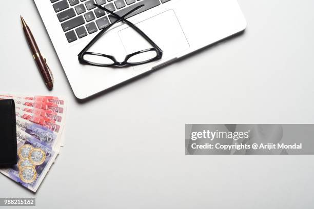 british banknotes pounds with laptop, pen, eyeglasses on office desk top view copy space - bringing home the bacon stock pictures, royalty-free photos & images