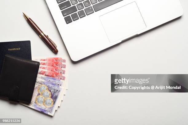 directly top view shot of british currency pound notes with passport, laptop, pen, money wallet copy space - bringing home the bacon engelse uitdrukking stockfoto's en -beelden