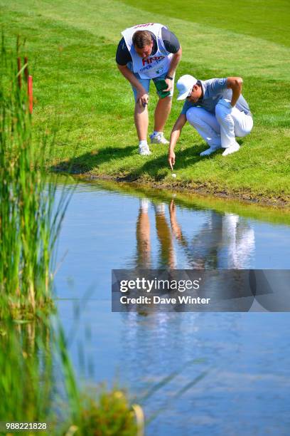 Haotong LI of China inspects his ball on the edge of a water hazard during the HNA French Open on June 30, 2018 in Saint-Quentin-en-Yvelines, France.