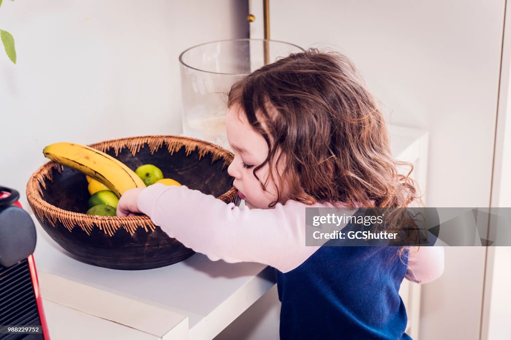 Curious toddler looking for her favorite fruit in a basket