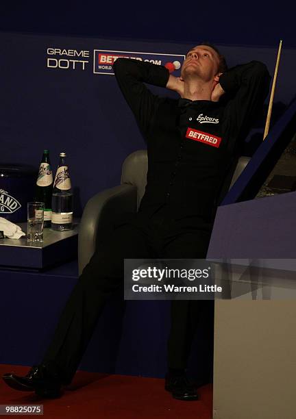 Dejected Graeme Dott of Scotland takes a seat as Neil Robertson of Australia plays during the final of the Betfred.com World Snooker Championships at...