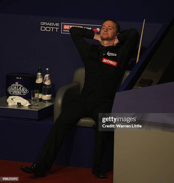 Dejected Graeme Dott of Scotland takes a seat as Neil Robertson of Australia plays during the final of the Betfred.com World Snooker Championships at...