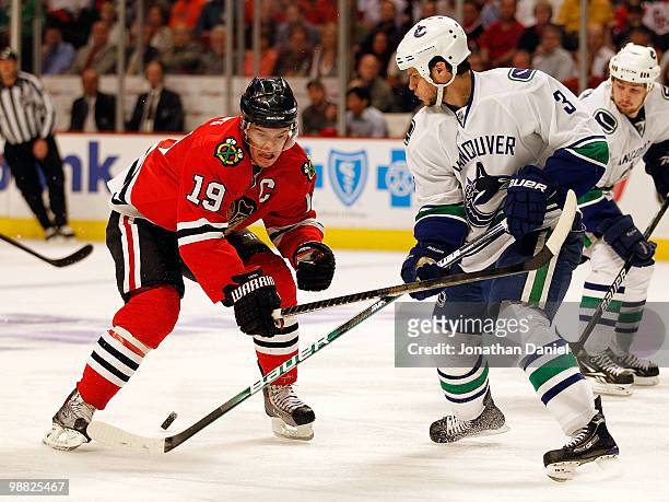 Kevin Bieksa of the Vancouver Canucks knocks the puck away from Jonathan Toews of the Chicago Blackhawks in Game Two of the Western Conference...