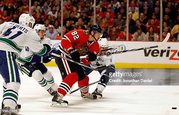 Tomas Kopecky of the Chicago Blackhawks pushes the puck up the ice under pressure from Andrew Alberts, Michael Grabner and Kevin Bieksa of the...