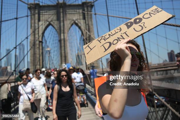 Demonstrators cross the Brooklyn Bridge as they take part in "Keep Families Together" march to protest President Donald J. Trump administration's...