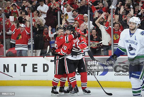 Patrick Sharp of the Chicago Blackhawks hugs teammate Kris Versteeg after tying the game in the third, as Ryan Kesler of the Vancouver Canucks skates...