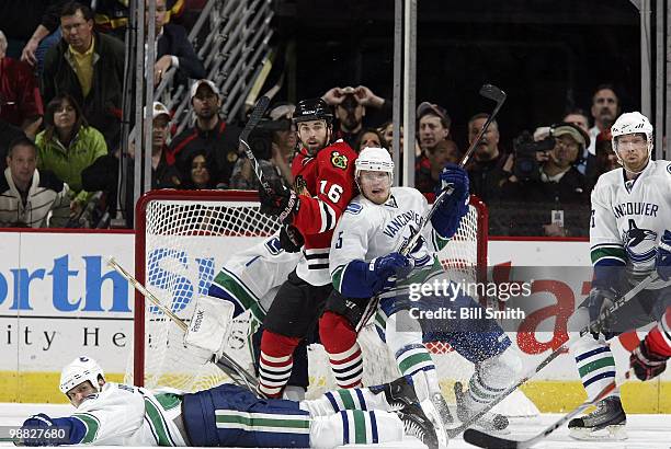 Andrew Ladd of the Chicago Blackhawks and Christian Ehrhoff of the Vancouver Canucks fight for position behind a fallen Kevin Bieksa of the Canucks,...