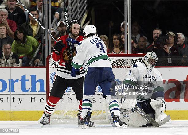 Andrew Ladd of the Chicago Blackhawks and Kevin Bieksa of the Vancouver Canucks start to shove into each other in front of Canucks goalie Roberto...