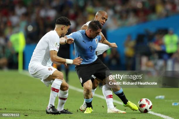 Cristian Rodriguez of Uruguay is challenged by Joao Mario and Pepe of Portugal during the 2018 FIFA World Cup Russia Round of 16 match between...