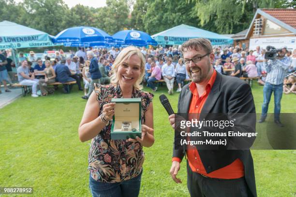 Saskia Greipl-Konstantinidis holding the first price in a lottery and actor André Horn during the Erich Greipl Tribute Tournament under the patronage...