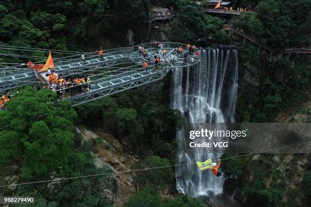 Aerial view of tourists visiting a glass bridge featuring a circular observation deck along a cliff at the Gulongxia scenic spot on June 28, 2018 in...