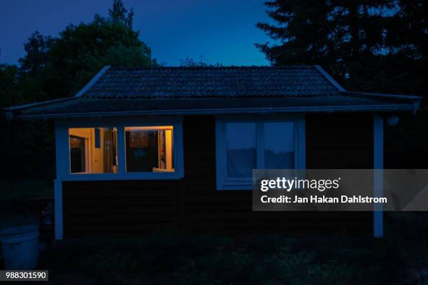 small cabin at night with illuminated window - shelter in place concept stock-fotos und bilder