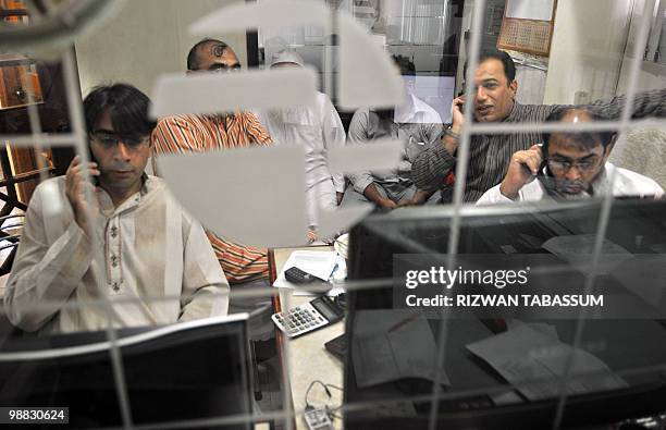 Pakistani stock dealers work at a brokerage house during a trading session in Karachi on May 4, 2010. The benchmark Karachi Stock Exchange 100 index...