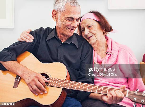 elderly couple in embrace playing guitar - newfamily stock pictures, royalty-free photos & images