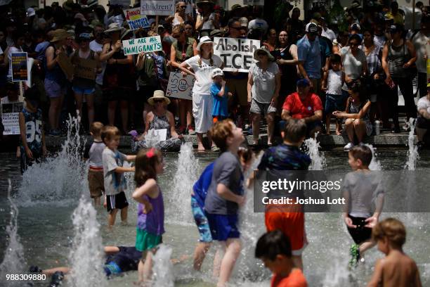 Demonstrators protest against Immigration and Customs Enforcement and the Trump administration's immigration policies as kids play in a fountain at...