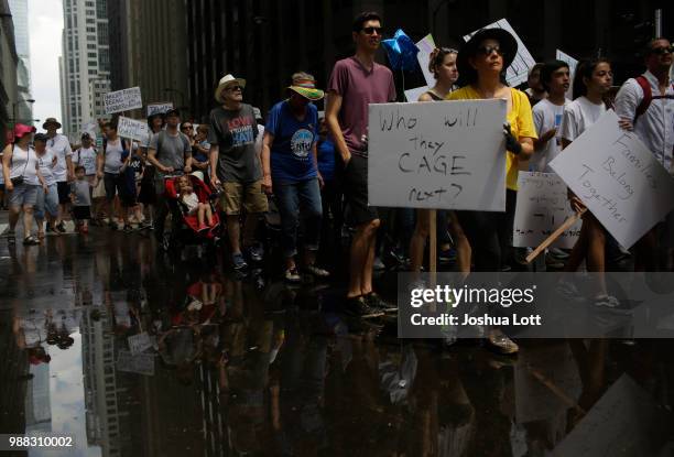 Demonstrators walk through water being sprayed from a fire truck as they protest against Immigration and Customs Enforcement and the Trump...