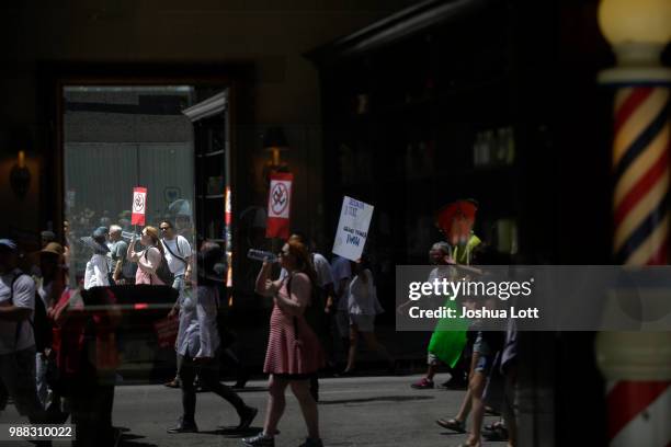 Demonstrators protesting against Immigration and Customs Enforcement and the Trump administration's immigration policies are reflected in a mirror...