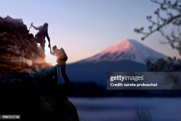 young asian couple  hikers climbing up on the peak of mountain near mountain fuji .climbing ,helps and team work concept . - climber hands bildbanksfoton och bilder