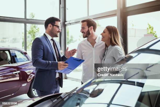 young couple buying a car - carro novo imagens e fotografias de stock