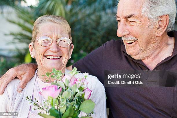 elderly couple sitting in garden, laughing - newfamily stock pictures, royalty-free photos & images
