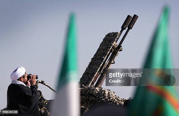 An Iranian clergyman looks through his binoculars as he stands behind an anti-aircraft gun during military exercises held at an unidentified location...