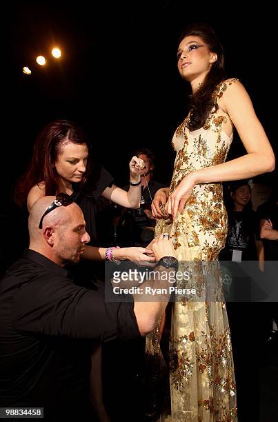 Designer Alex Perry sews a model into one of his dresses backstage ahead of the Alex Perry collection show on the second day of Rosemount Australian...