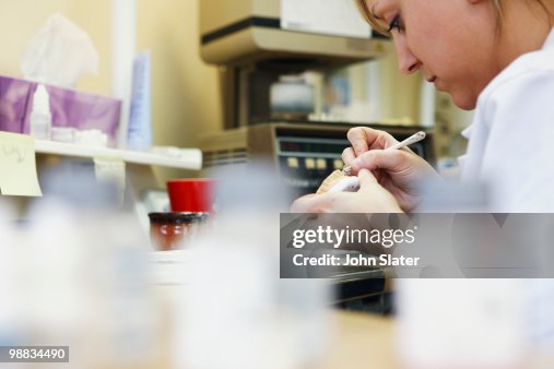 Lab worker at bench using tool Lab worker at bench using tool