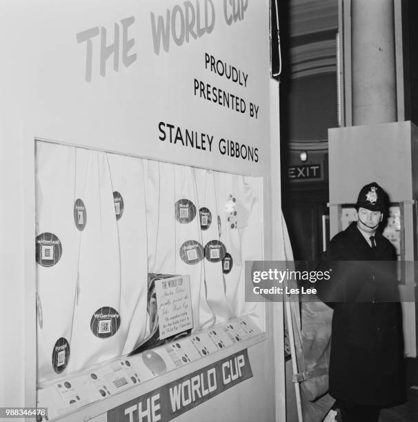 Policeman stands guard in Central Hall Westminster, next to the stand at the National Stamp Exhibition where the FIFA World Cup Jules Rimet trophy...