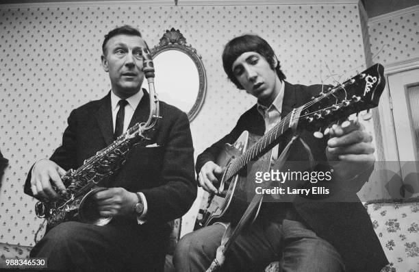 Pete Townshend of The Who pictured playing an acoustic guitar with his father Cliff Townshend , saxophone player with the Squadronaires, at home in...