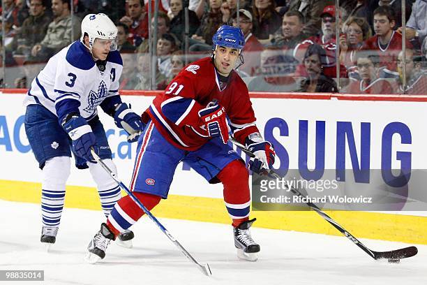 Scott Gomez of the Montreal Canadiens skates with the puck while being defended by Dion Phaneuf of the Toronto Maple Leafs during the NHL game on...