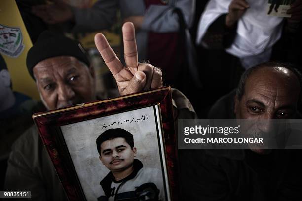 Palestinian father flashes the victory sign as he holds a picture of his son during a protest in Gaza City calling for the release of Palestinian...