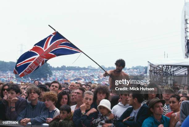 The audience at Glastonbury Festival with one man waving a Union Jack flag in June 1995.