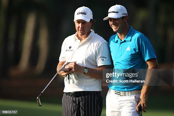 Phil Mickelson talks with Dustin Johnson as he looks at his yardage book during a practice round prior to the start of THE PLAYERS Championship held...