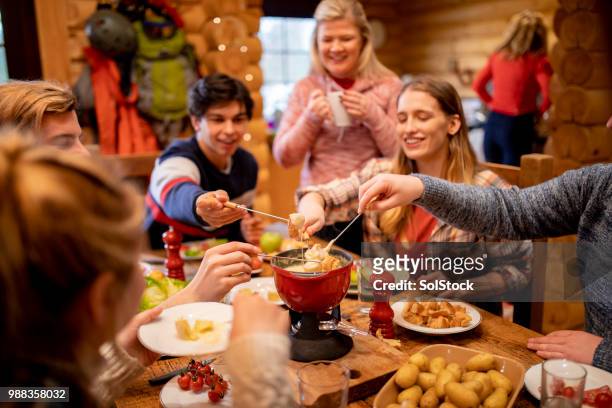 freunde essen fondue beim abendessen - fondue stock-fotos und bilder