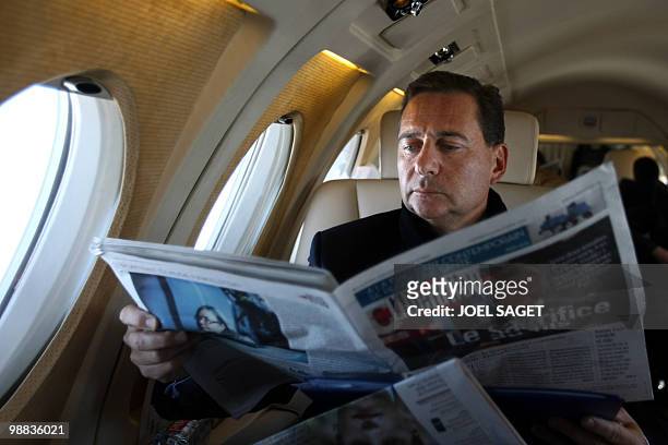 French minister for immigration Eric Besson reads the French daily "Liberation" on October 23, 2009 on a plane taking him to Almeira in Spain to...