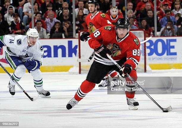 Patrick Kane of the Chicago Blackhawks takes the puck up the ice as Alexandre Burrows of the Vancouver Canucks chases behind at Game One of the...