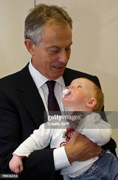 Former British Prime Minister Tony Blair holds an 11-month-old baby, Paisley Jade Ashton-Woods, during an election campaign visit for the Labour...