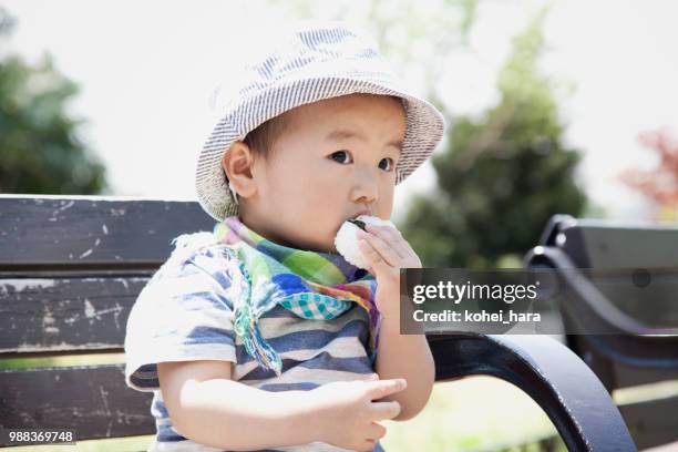 jongen eten een rijst bal in het park - rice ball stockfoto's en -beelden