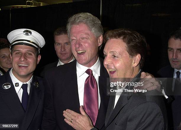 Bill Clinton and Paul McCartney backstage with police officers and fire fighters.