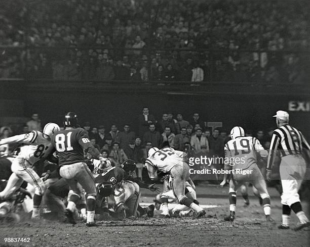 Alan Ameche of the Baltimore Colts carries the ball for the game winning touchdown against Cliff Livingston and Emlen Tunnell of the New York Giants...