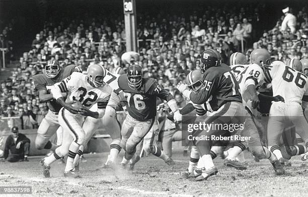 Jim Brown of the Cleveland Browns carries the ball against Rosey Davis, John LoVetere and Jim Katcavage of the New York Giants during the game at...