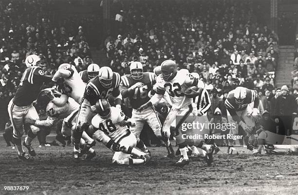 Jim Brown of the Cleveland Browns carries the ball as Dick Schafrath, Johnny Brewer and Ernie Green block against Ordell Braase, Don Shinnick and...