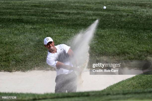 Tiger Woods hits out of a bunker on the 18th hole during the third round of the Quicken Loans National at TPC Potomac on June 30, 2018 in Potomac,...