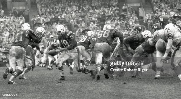 Johnny Unitas of the Baltimore Colts hands off to Tom Matte as J.W. Lockett, John Mackey, Alex Sandusky and Jim Parker block during the game against...