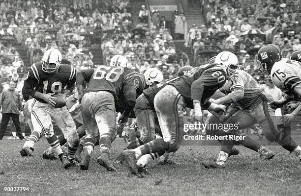 Johnny Unitas of the Baltimore Colts drops back to pass as Alex Sandusky and George Preas block during the game against the New York Giants at...