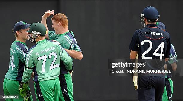 Ireland cricketers William Porterfield, Niall O'Brien amd teammate Kevin O'Brien recats after taking the wicket of England cricketer Kevin Pietersen...