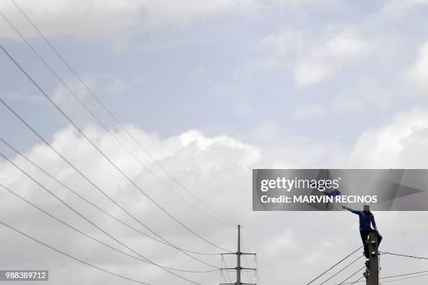 Man flutters a Nicaraguan national flag during the "Marcha de las Flores" -in honor of the children killed during protests- in Managua on June 30,...