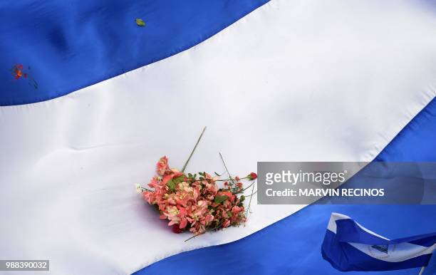 Flowers are seen on a Nicaraguan national flag during the "Marcha de las Flores" -in honor of the children killed during protests- in Managua on June...